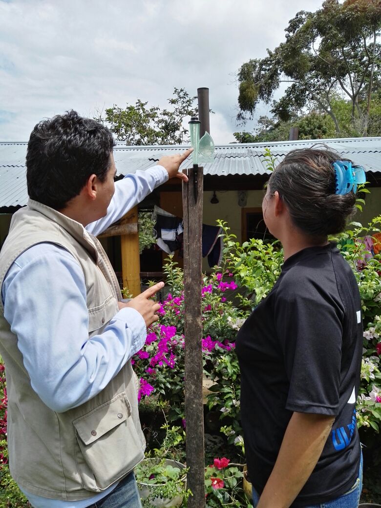 Mitchel Hernandez Agronomo explica pluviometro a campesina